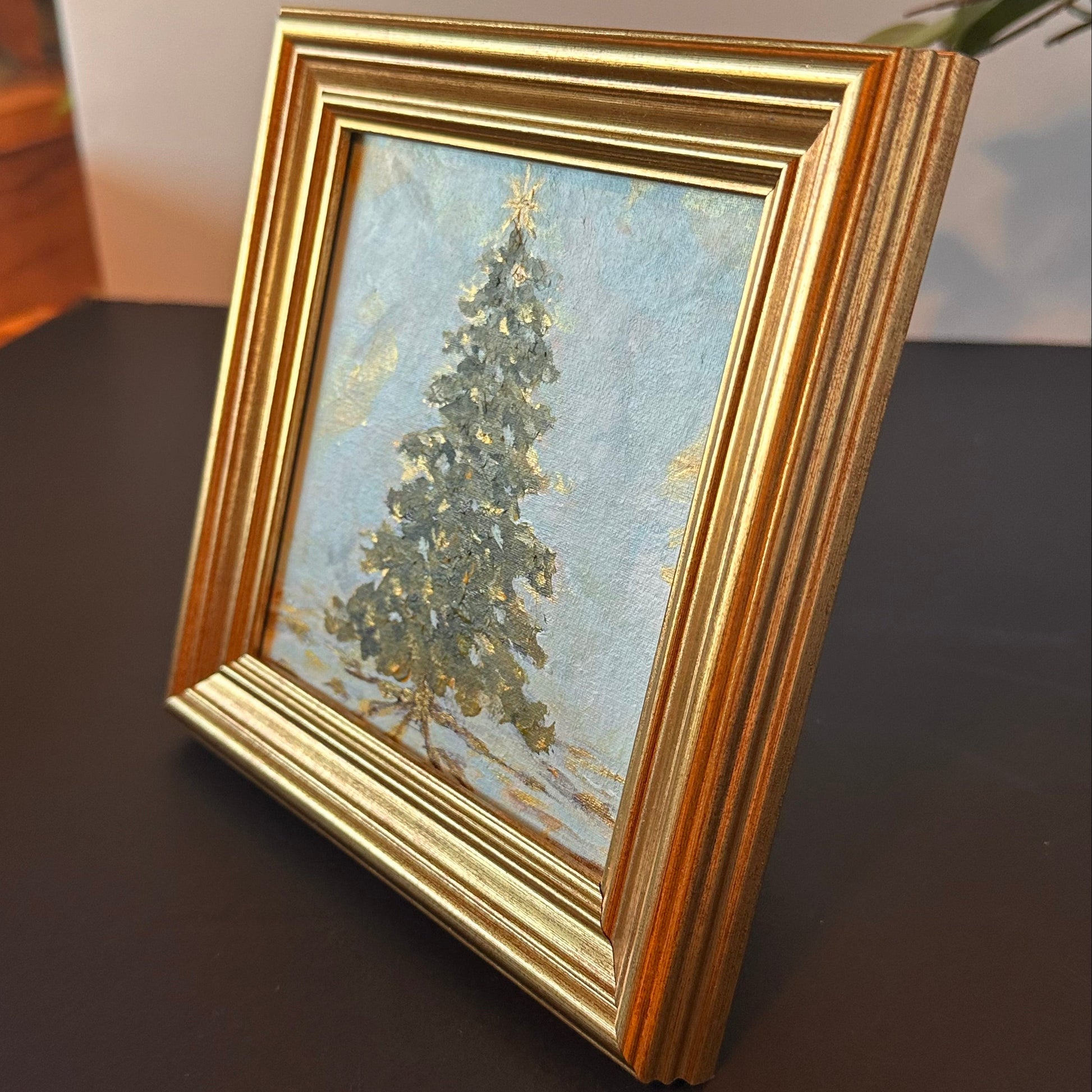 Framed painting of a tree on a dark surface